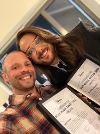 Queermentor Role Model Awards Preisträger Nils Binder und Riccardo Simonetti lächeln in die Kamera und halten ihre Urkunden in die Kamera.