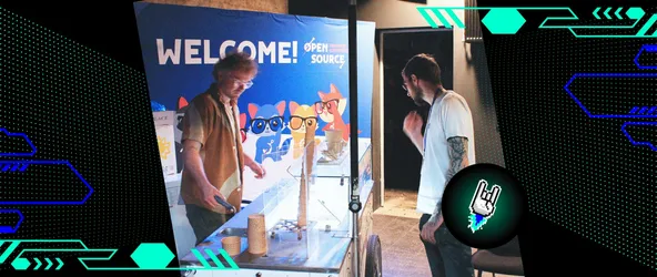 Foto vom Eingangsbereich der OSFC 2024. Zwei Männer, die vor dem Banner mit "Welcome Open Source 2024" stehen und die Theke anschauen.